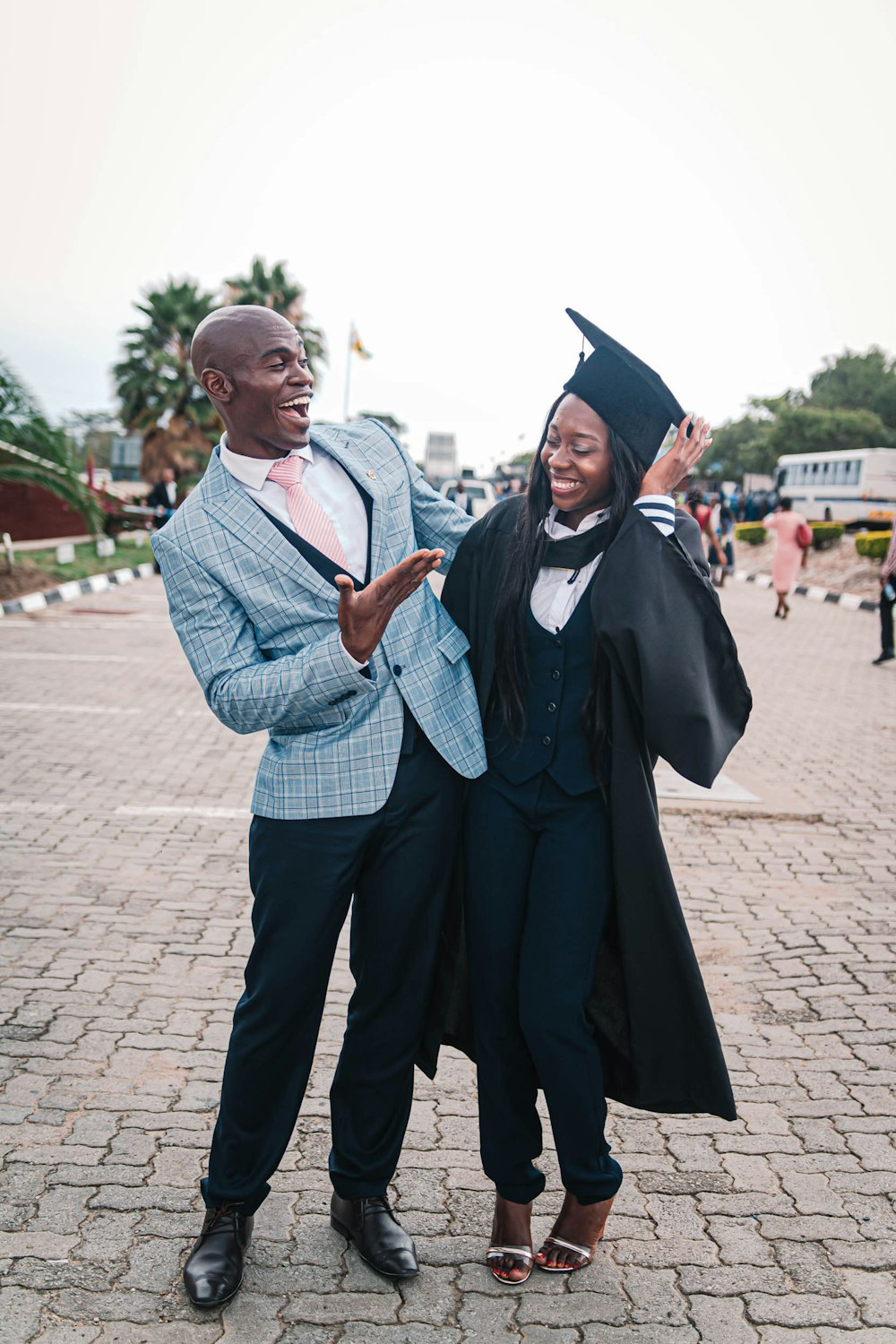 man in black academic gown beside man in blue and white plaid button up shirt