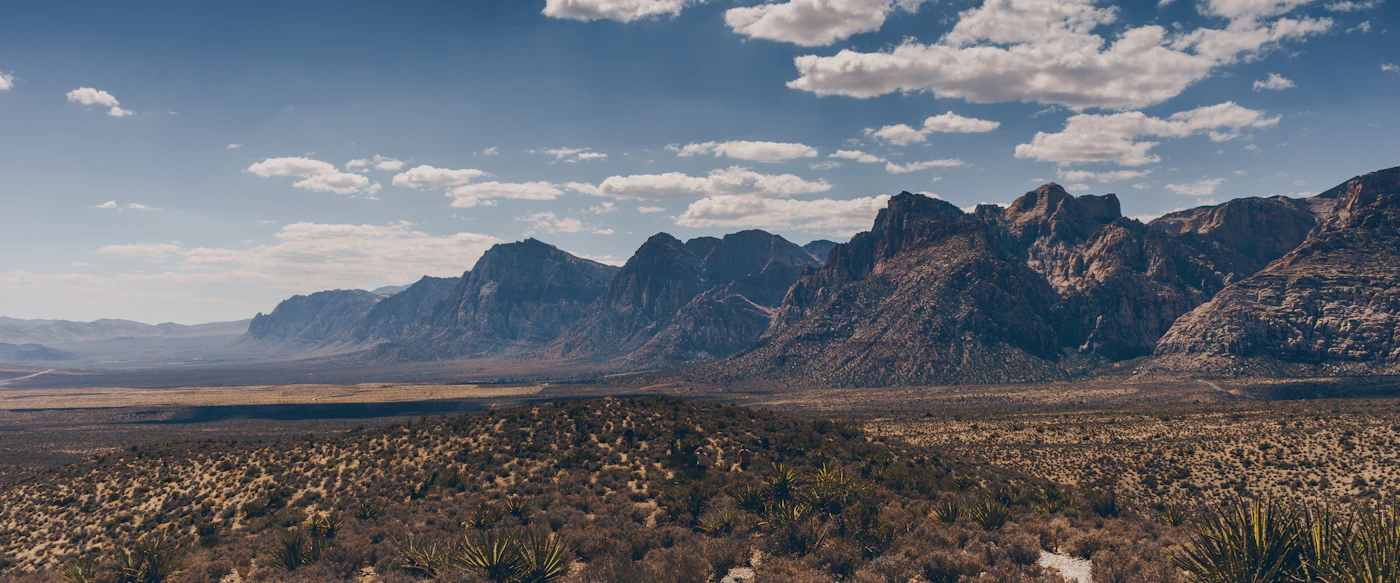 Rugged desert mountains rising above open foothills under a blue sky