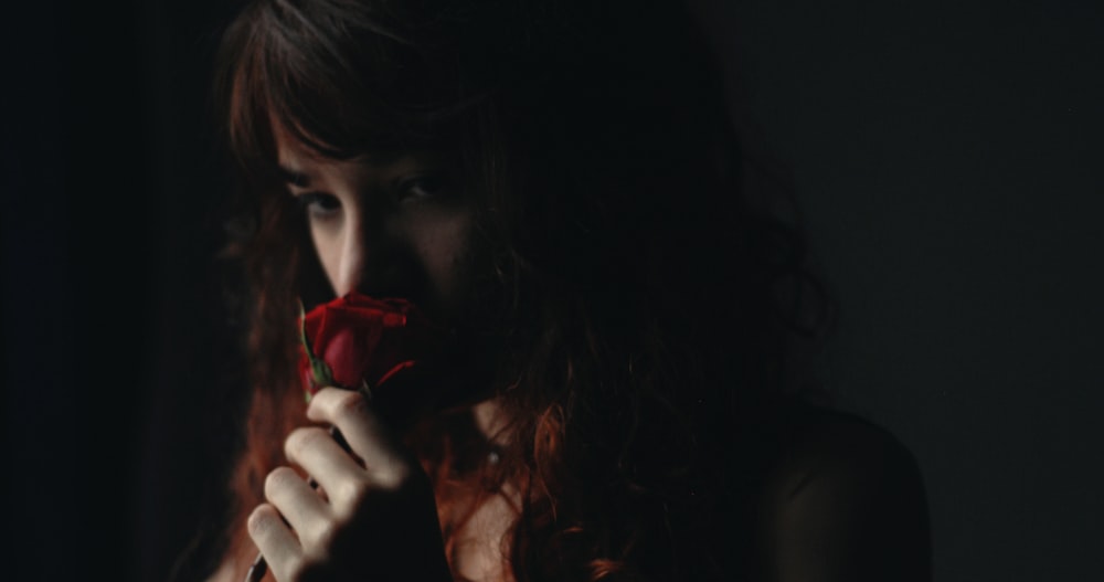 woman in black shirt holding red rose
