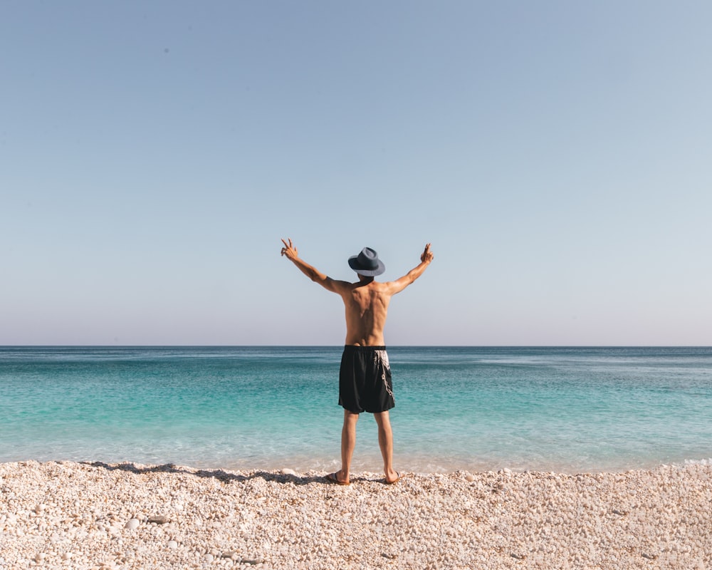 man in black shorts standing on beach during daytime