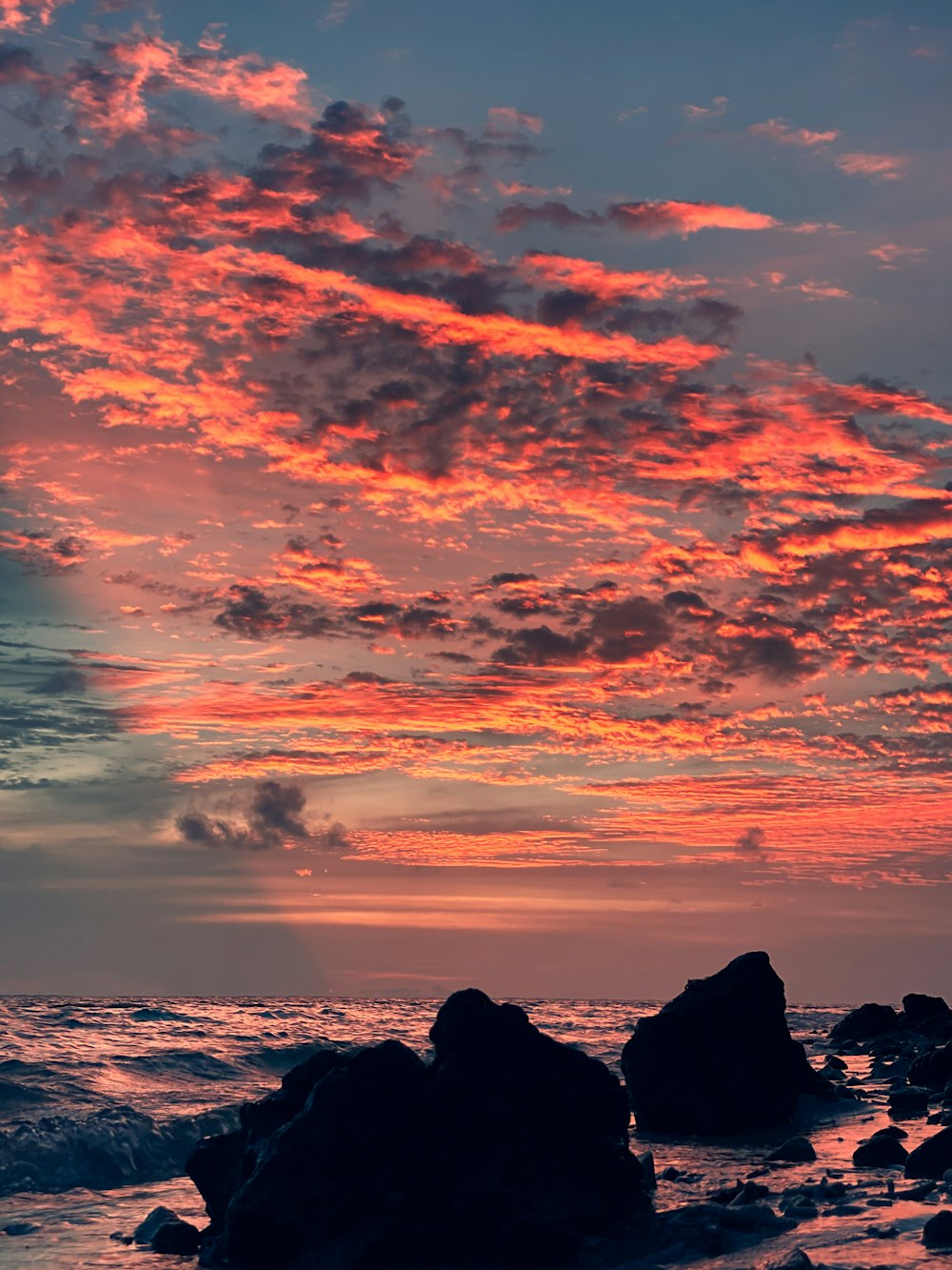 silhouette of rock formation under cloudy sky during sunset