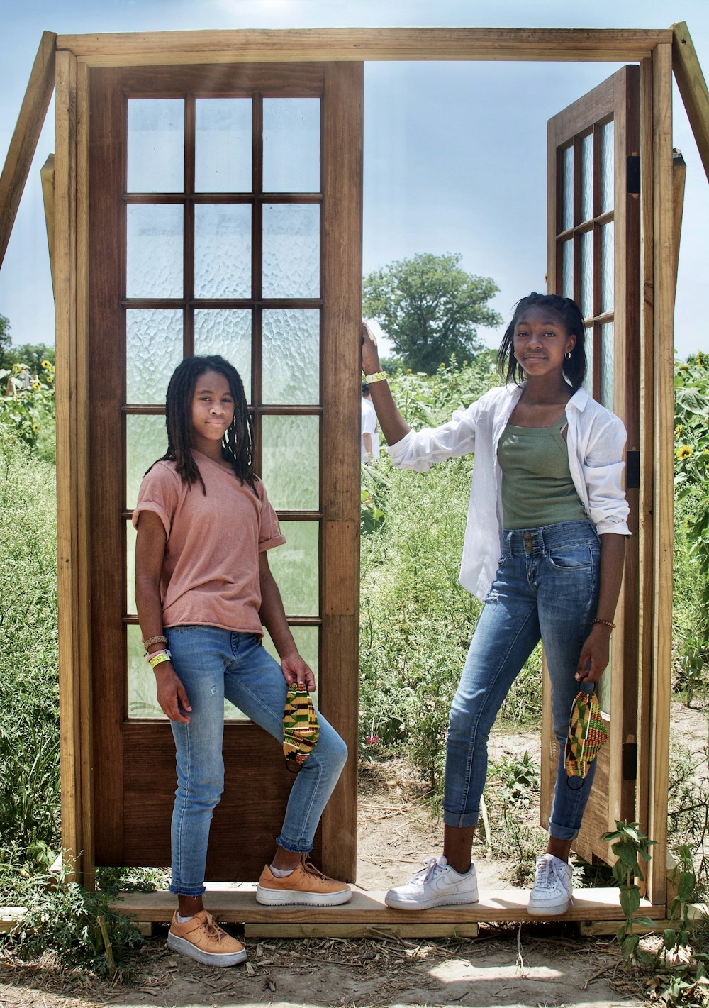 2 women standing beside brown wooden framed glass window during daytime