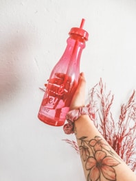 person holding red plastic bottle