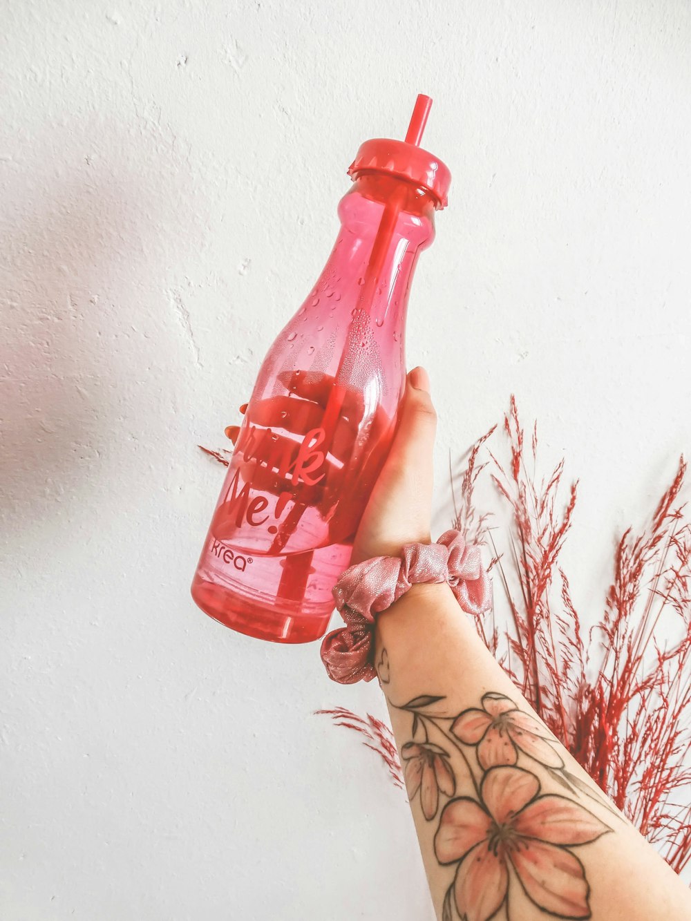 person holding red plastic bottle