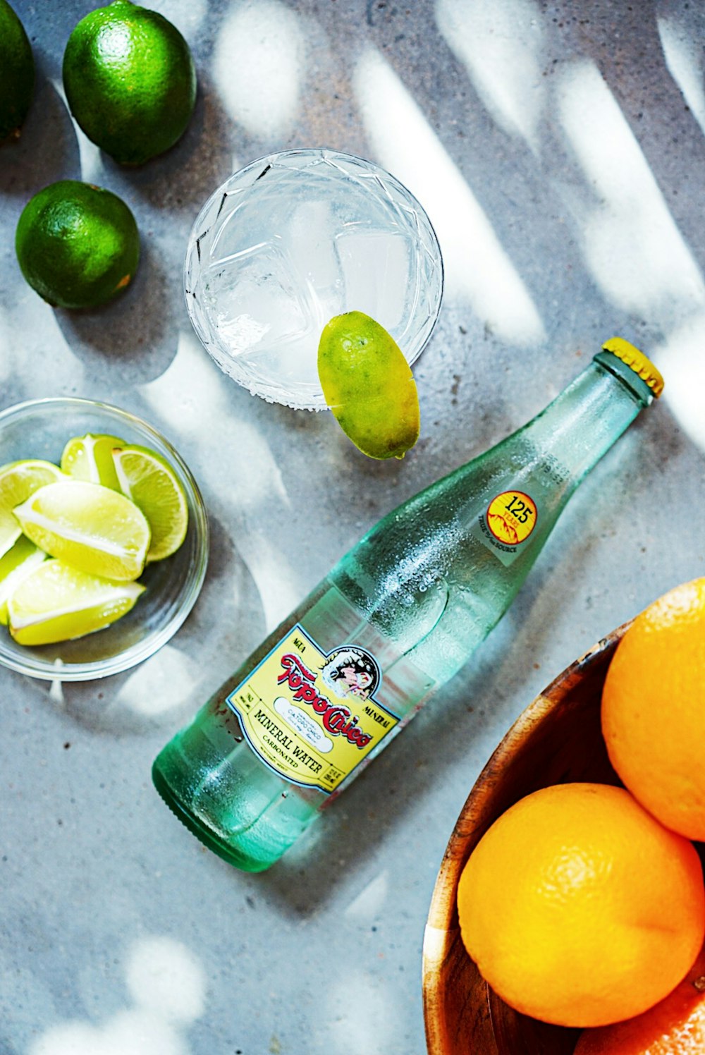 green glass bottle beside orange citrus fruit