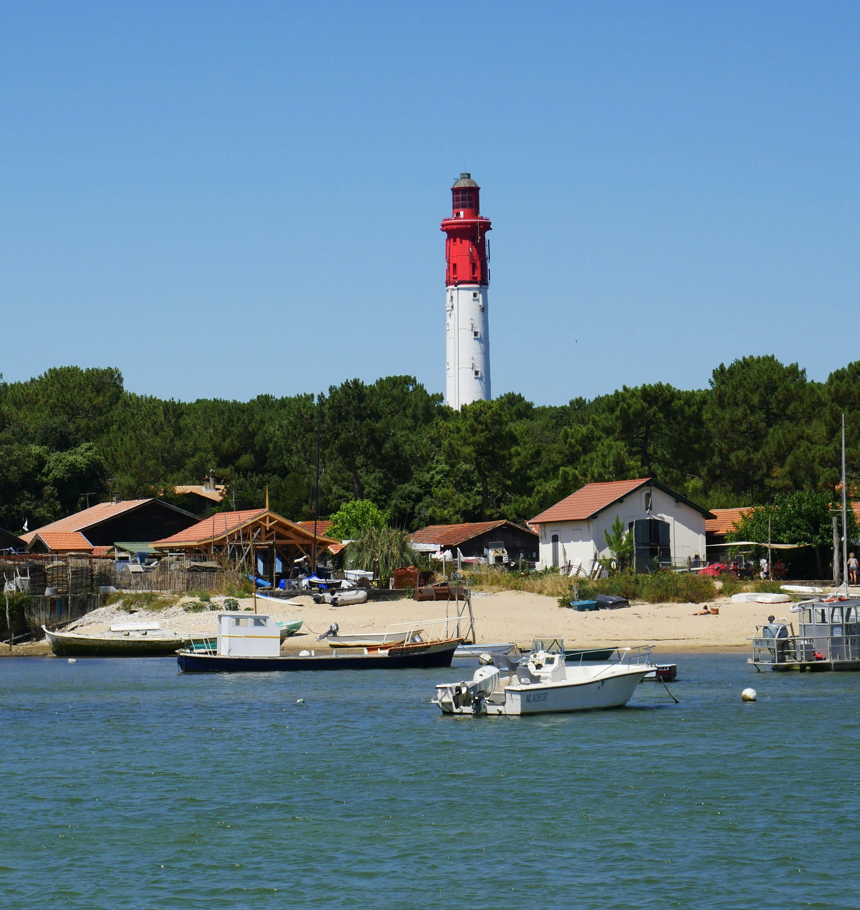 white and red lighthouse near body of water during daytime