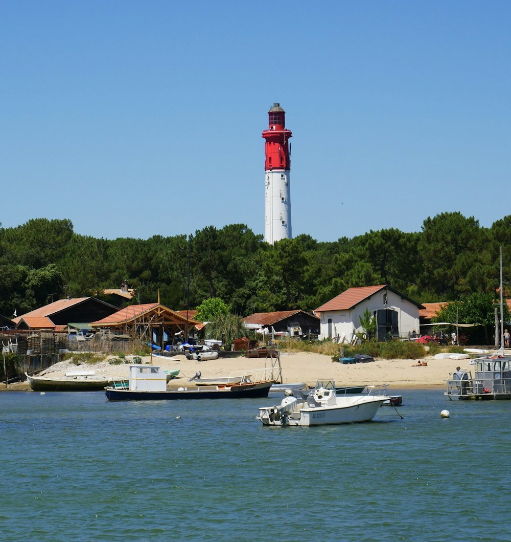 Weißer und roter Leuchtturm in der Nähe des Gewässers tagsüber