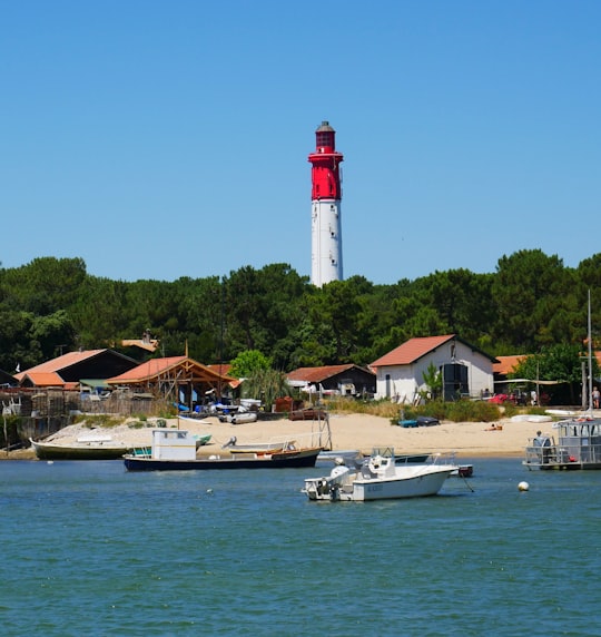 white and red lighthouse near body of water during daytime in Cap Ferret France