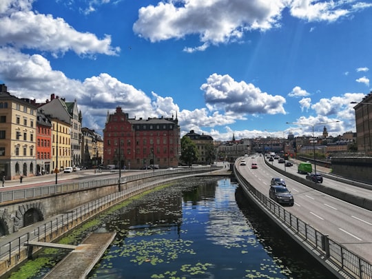 brown and white concrete building near river under blue and white sky during daytime in Riddarholmskyrkan Sweden