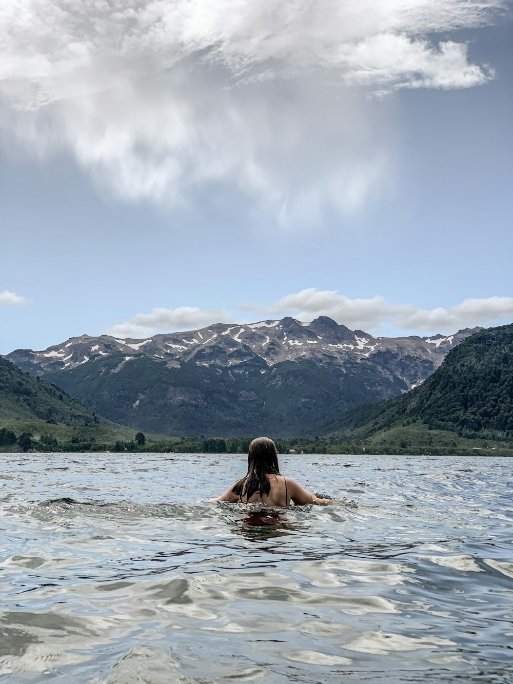 mulher na água perto da montanha durante o dia