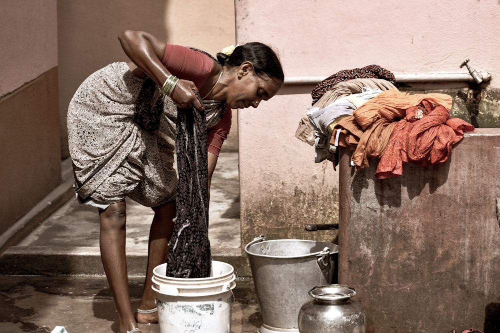 woman in black and brown dress holding white plastic bucket