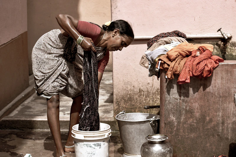 Indian woman in black and brown dress holding a bucket