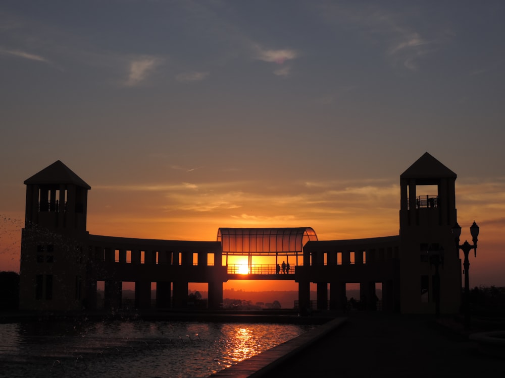 Weißes und braunes Betongebäude in der Nähe von Gewässern bei Sonnenuntergang