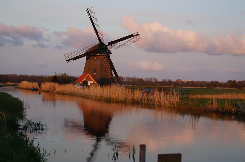 brown windmill near body of water during daytime
