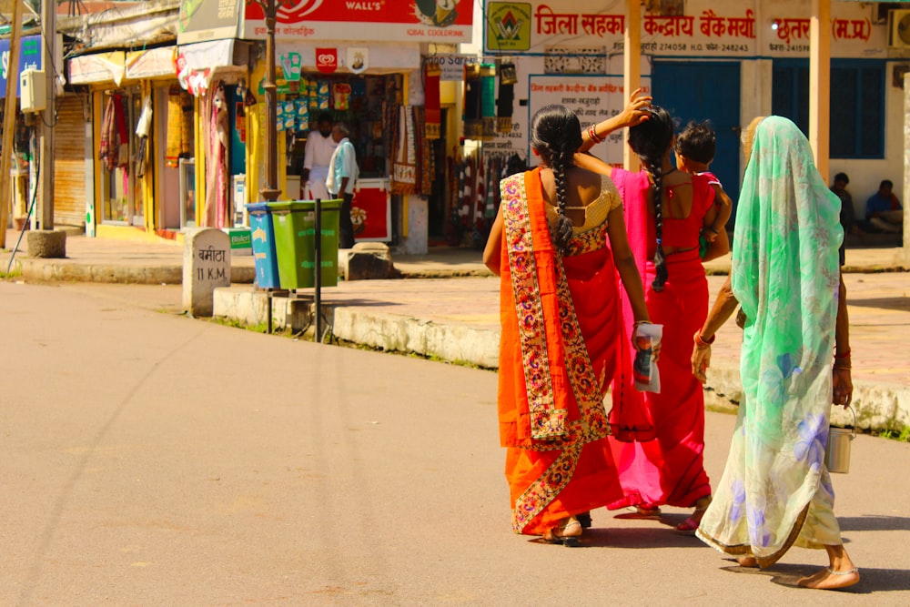 昼間、歩道を歩く赤と白のサリードレスを着た女性