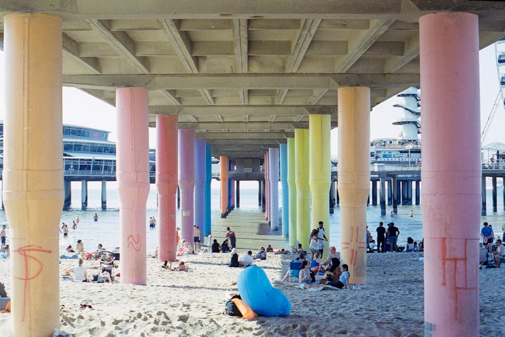 people sitting on white sand near body of water during daytime