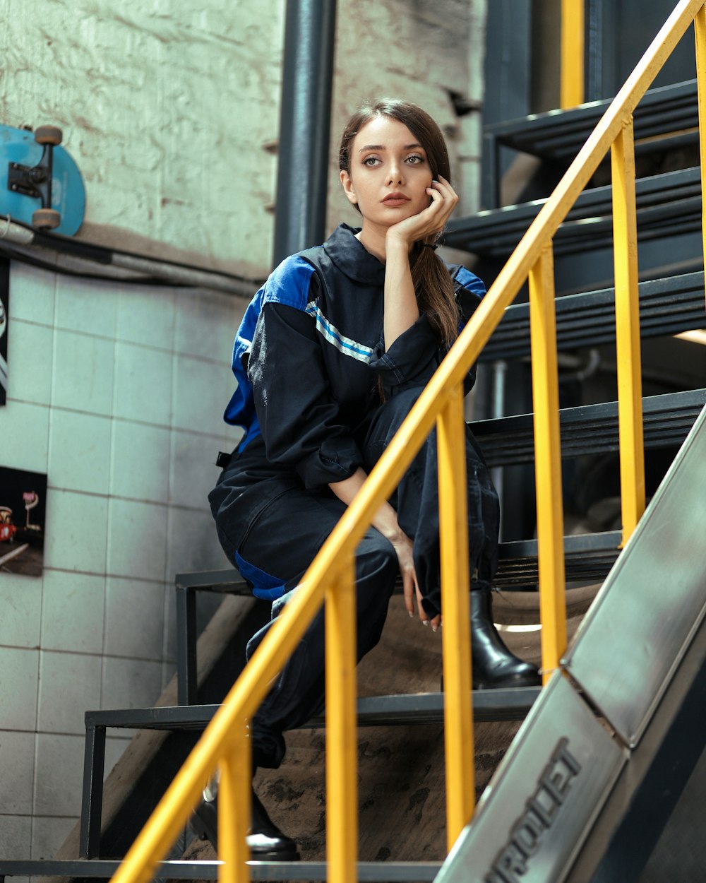 woman in blue and black jacket standing beside yellow metal railings