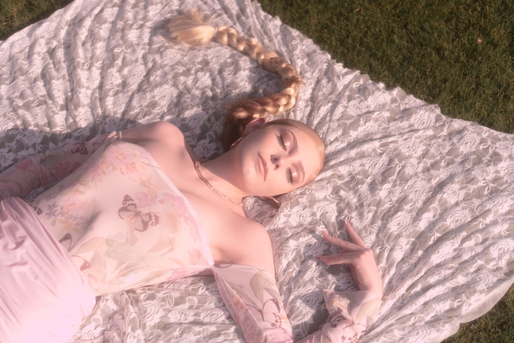 woman in white floral dress lying on white textile
