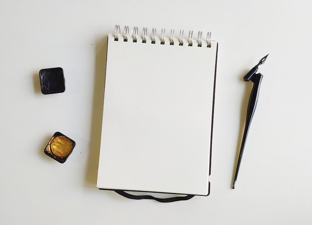 white notebook beside black and silver scissors