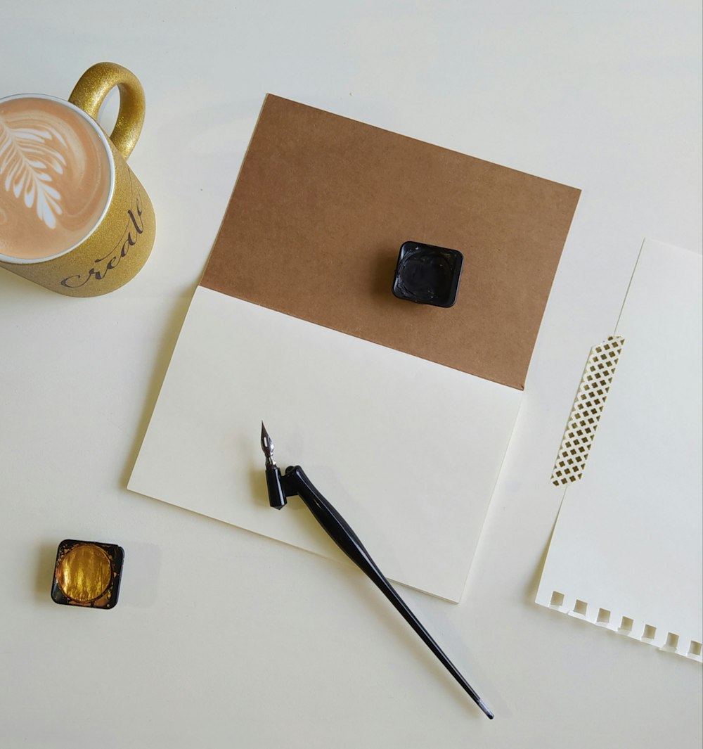 silver and gold watch beside brown ceramic mug on white table