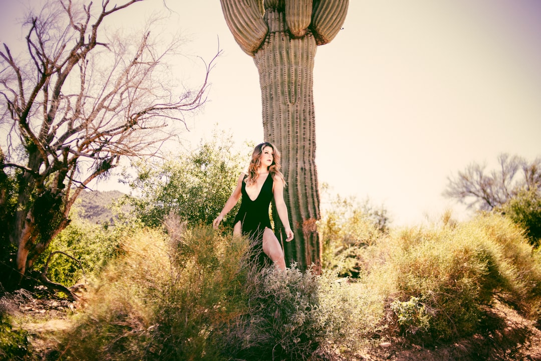 woman in black dress standing beside brown tree during daytime