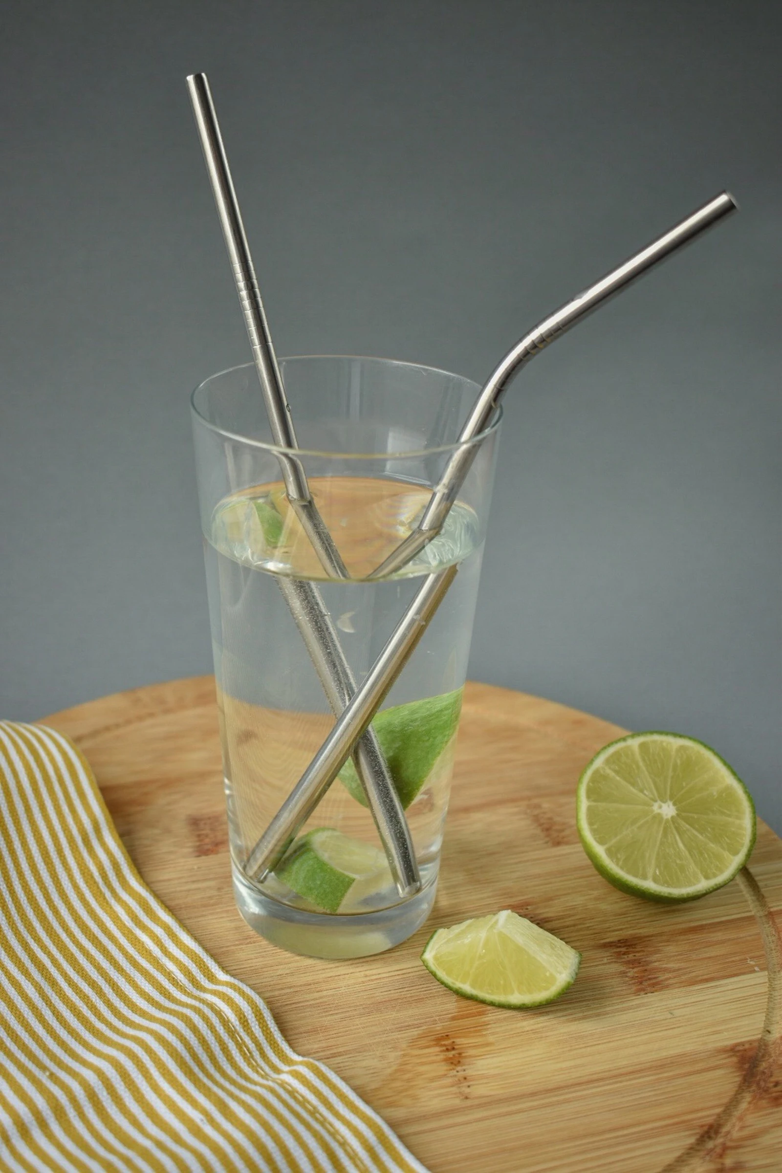 Cold drink with sliced lemon and a straw on a wooden coaster