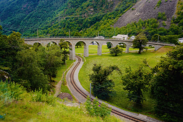 gray concrete bridge over green mountain during daytime