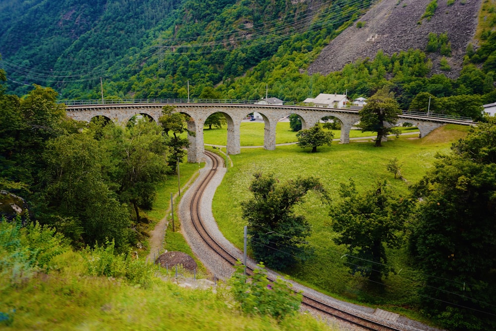 gray concrete bridge over green mountain during daytime