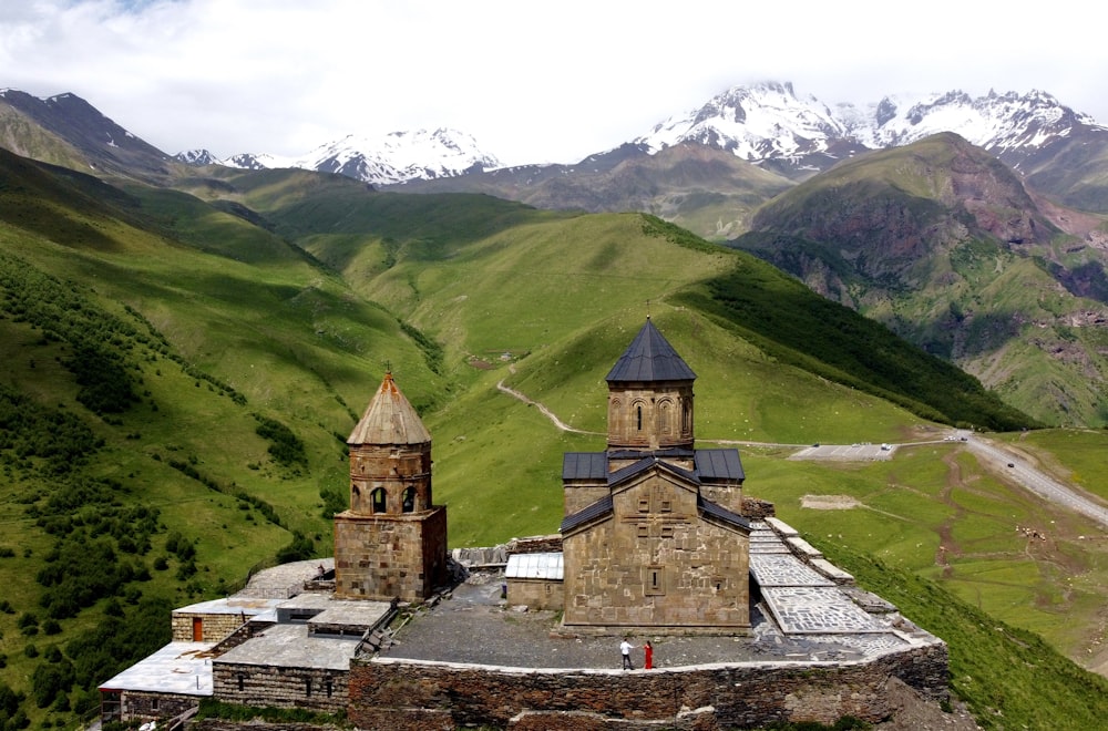 edificio in mattoni marroni sul campo di erba verde vicino alla montagna durante il giorno