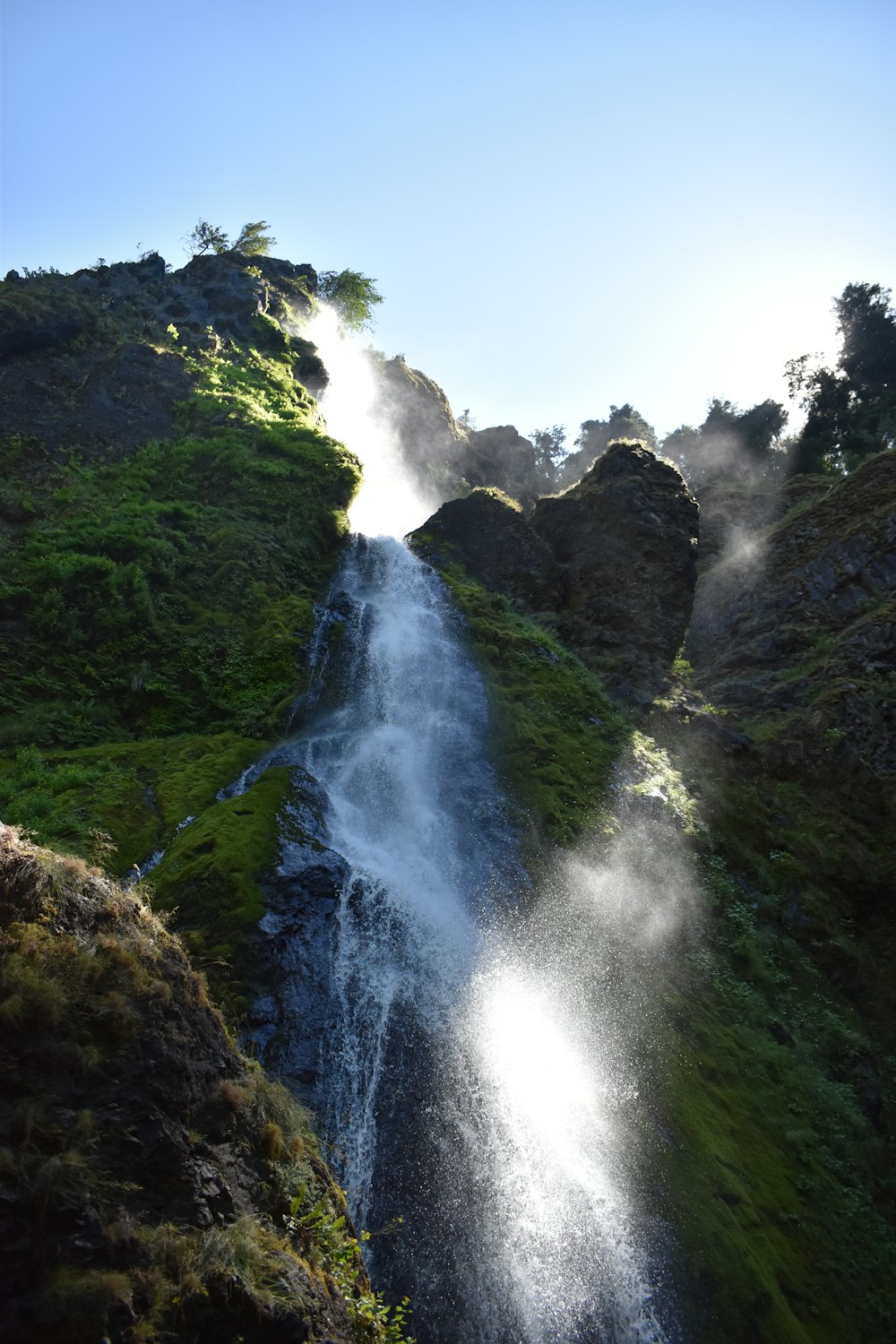 green mountain with waterfalls under blue sky during daytime