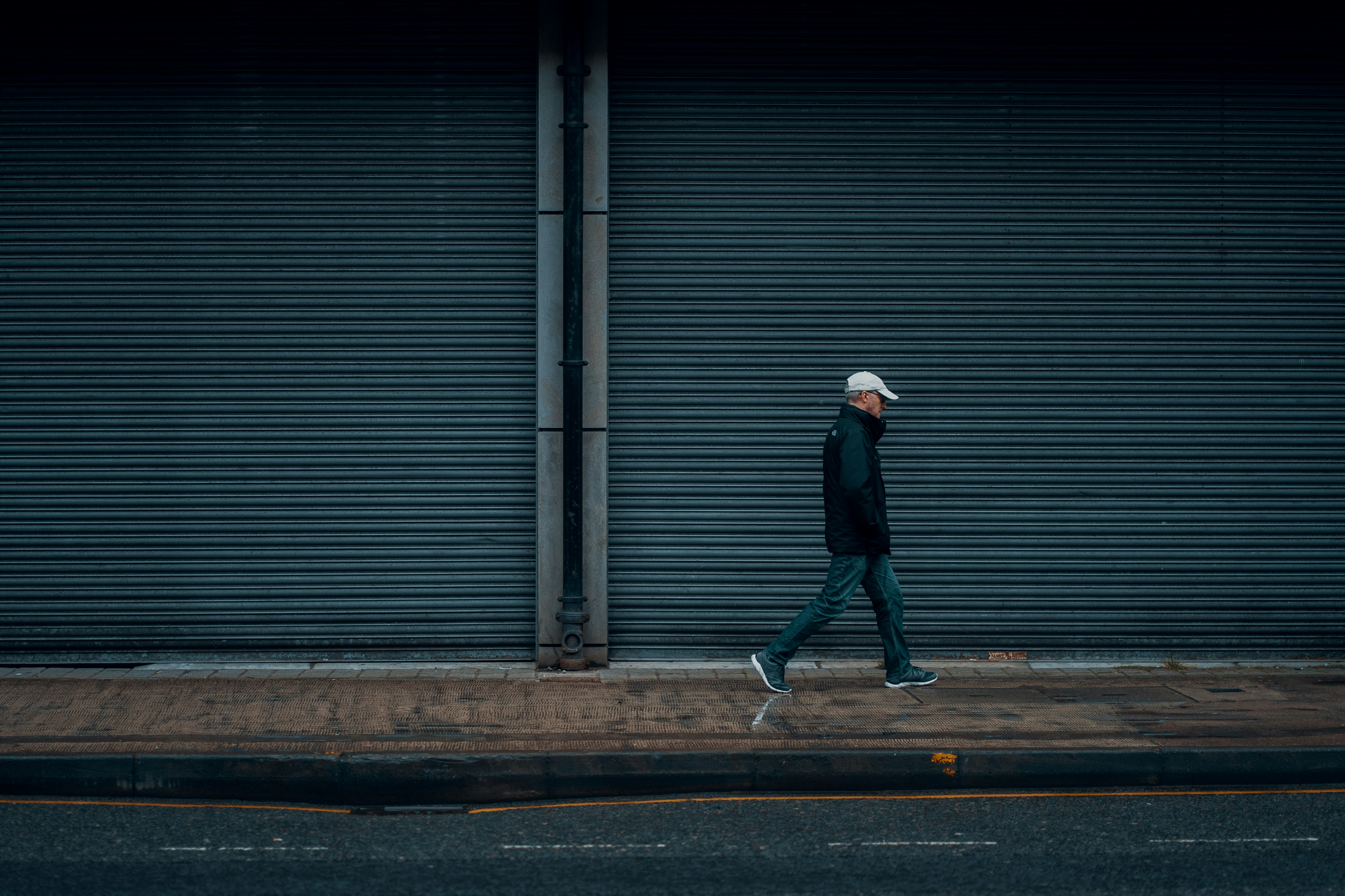 man in black jacket walking on sidewalk during daytime