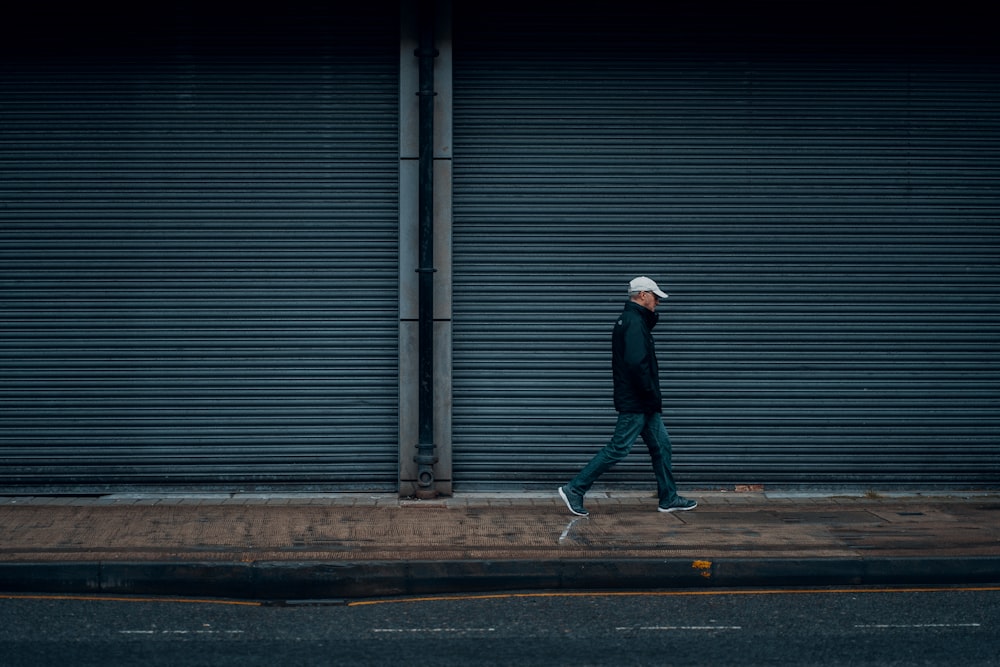 man in black jacket walking on sidewalk during daytime