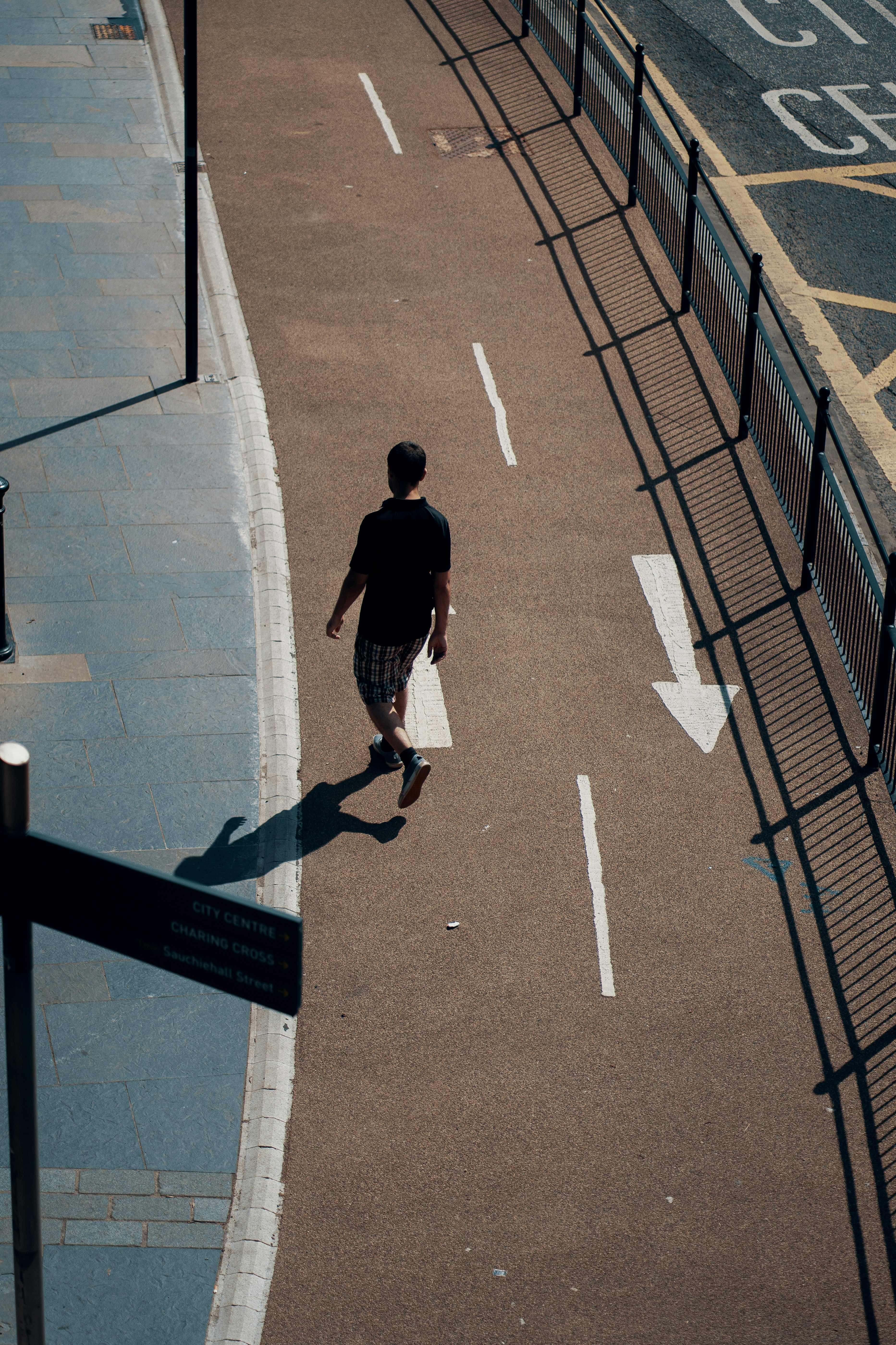 man in black t-shirt and blue denim jeans walking on gray concrete pavement during daytime