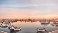 Morning light casting golden hues on a quiet harbor filled with colorful fishing boats.