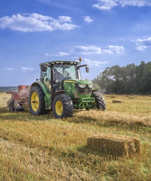 green tractor on brown grass field under blue sky during daytime