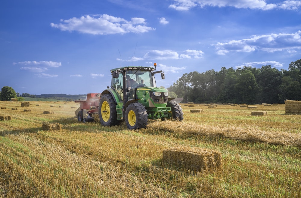 Grüner Traktor tagsüber auf braunem Rasenfeld unter blauem Himmel