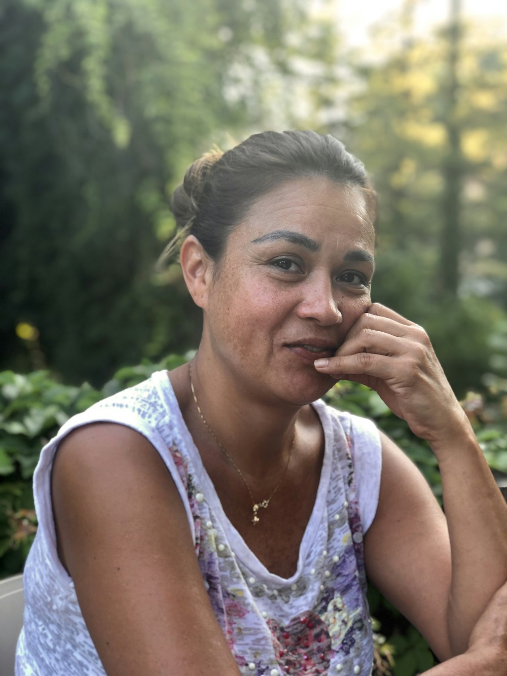 woman in white tank top holding her face