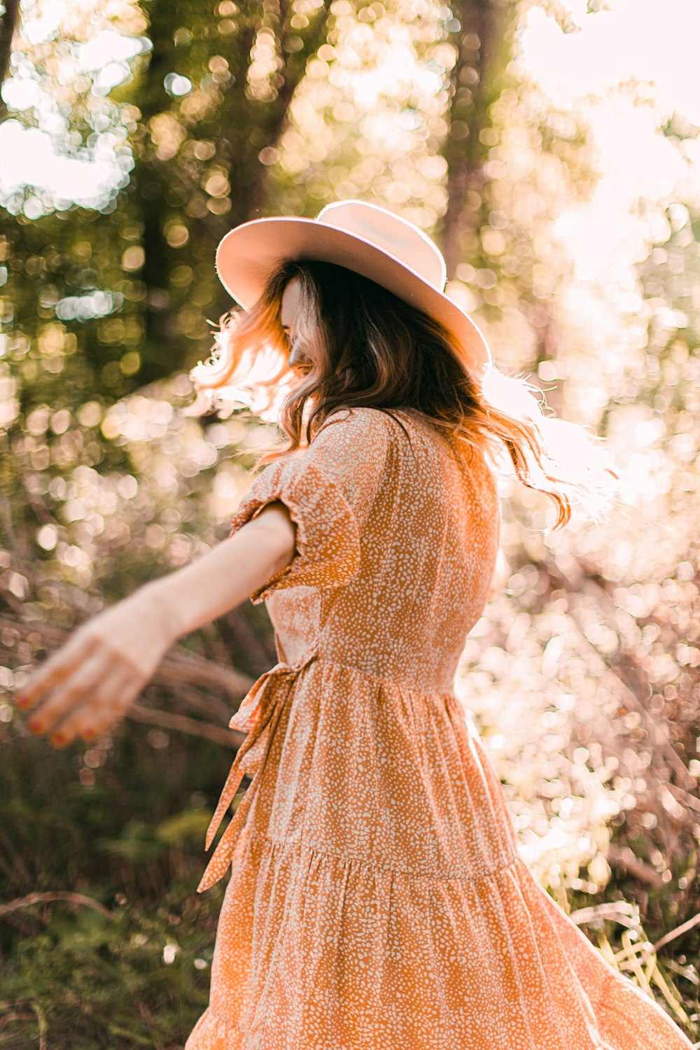 Femme en robe marron et blanche portant un chapeau marron debout près de fleurs blanches pendant la journée