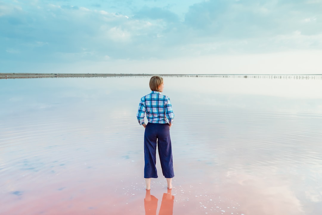 boy in blue and white plaid shirt and blue shorts standing on water during daytime