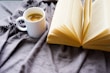 A cozy living room setting with a muted beige mug on a side table next to an open book.