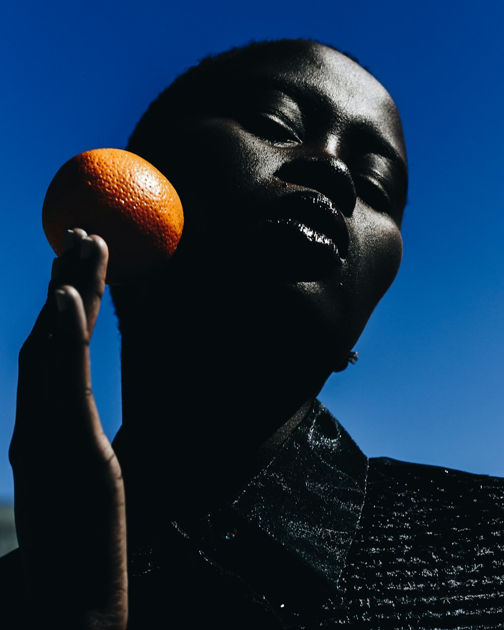 mulher que segura a fruta laranja durante o dia