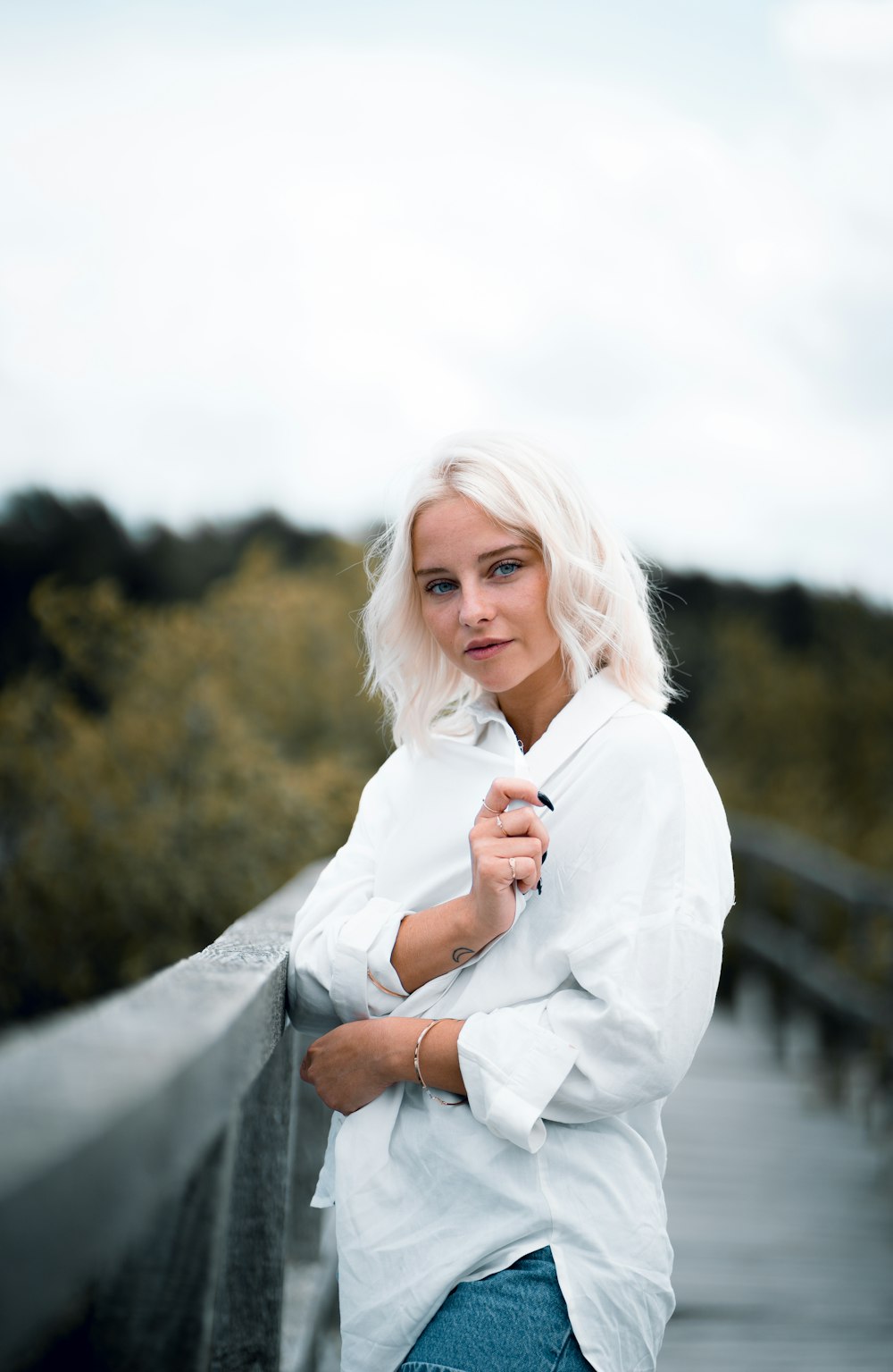 woman in white long sleeve shirt standing on gray concrete pavement during daytime