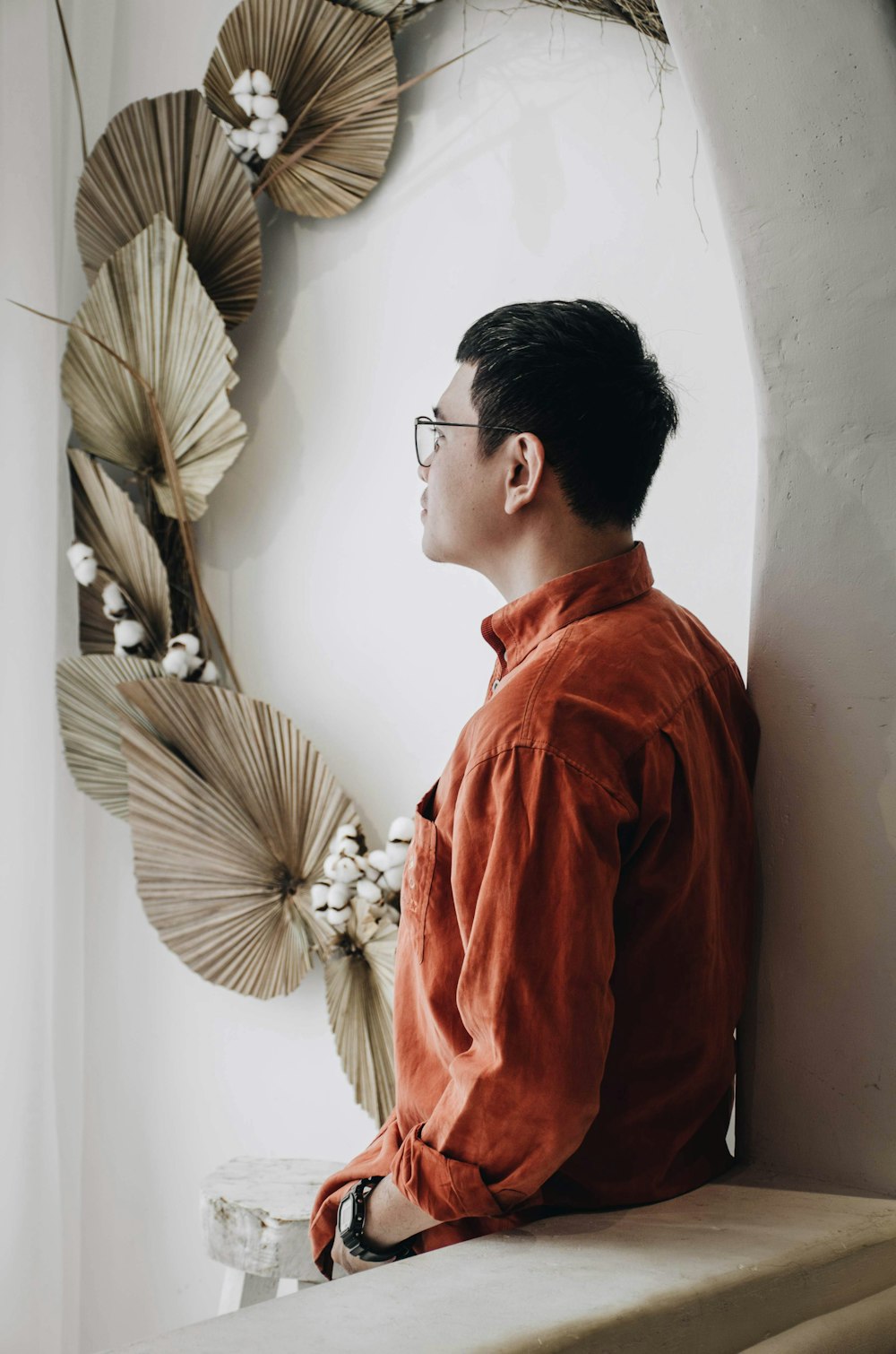 man in red long sleeve shirt standing beside white wall