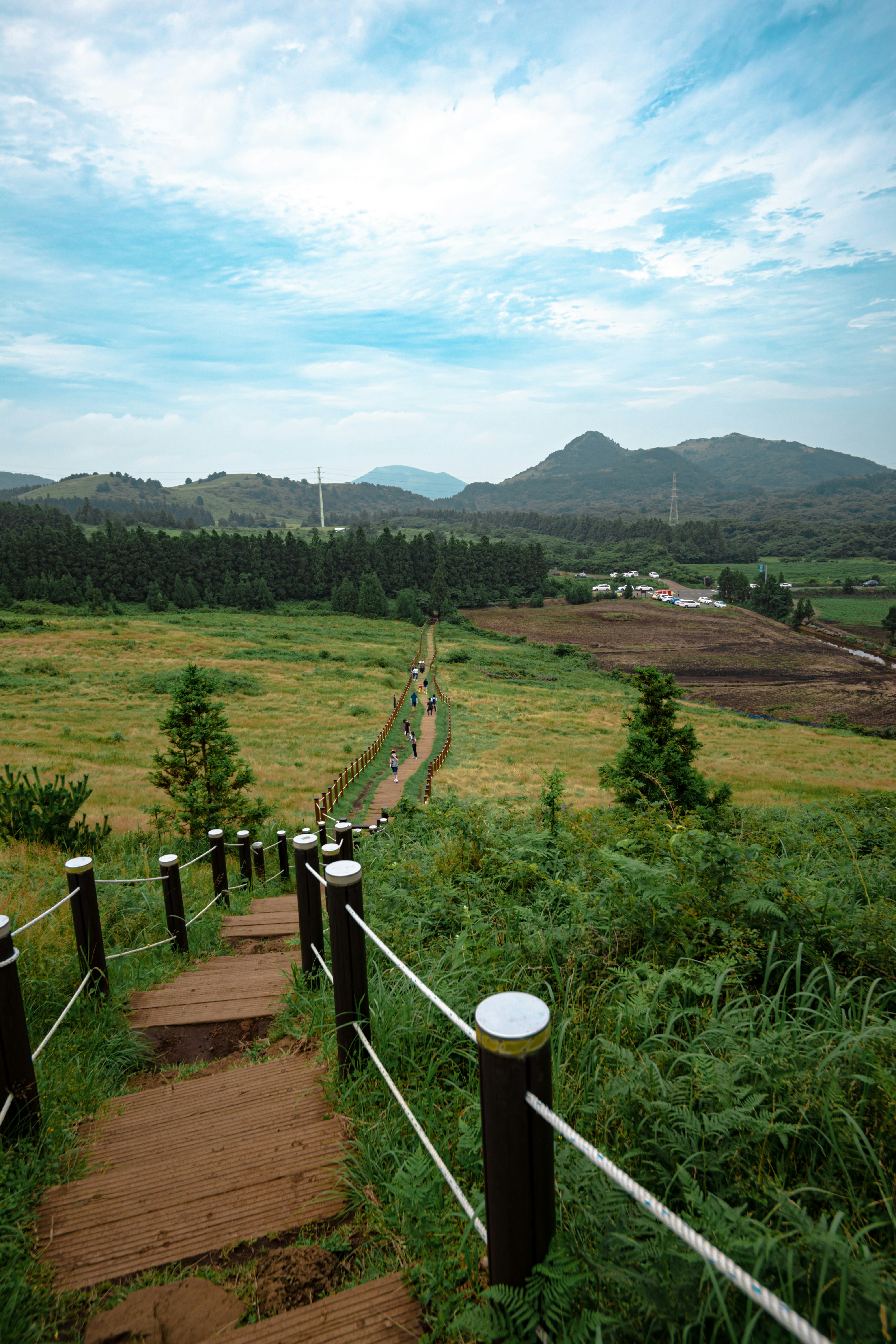 green grass field near mountain under blue sky during daytime