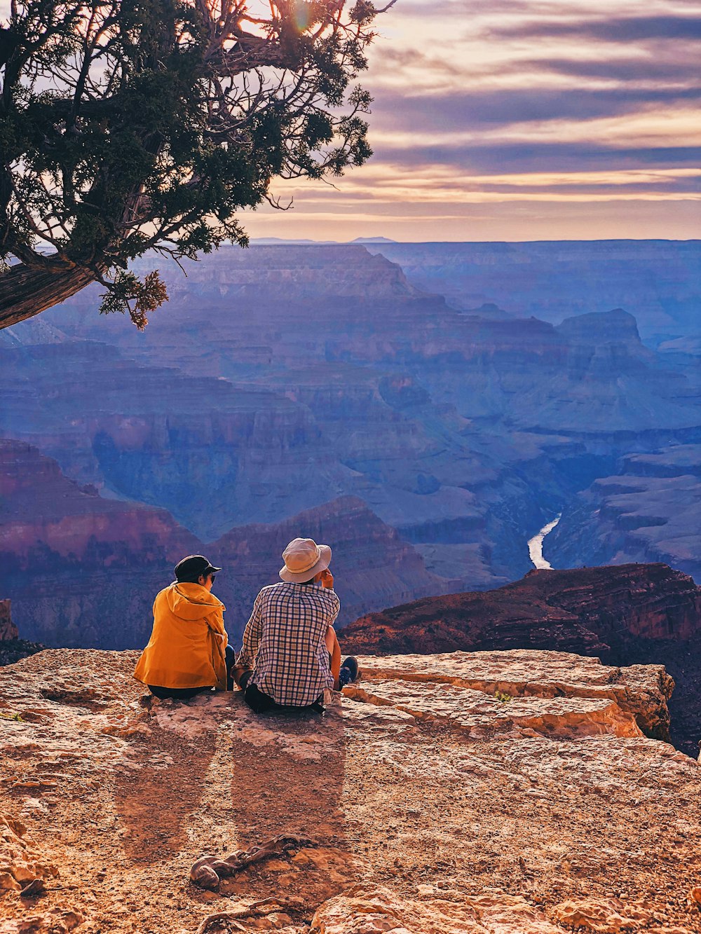 2 person sitting on brown rock formation during daytime