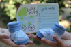 person holding white paper with green and blue floral hand fan