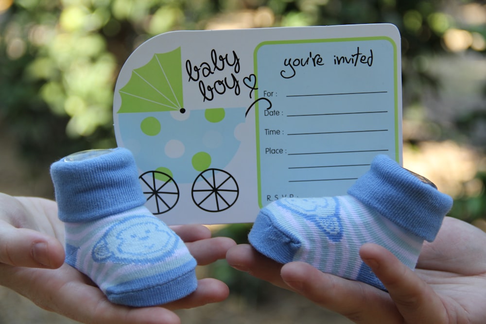 person holding white paper with green and blue floral hand fan