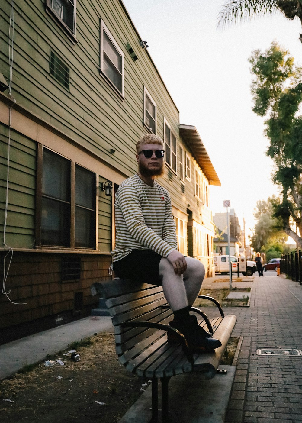 man in black and white striped long sleeve shirt sitting on brown wooden bench during daytime