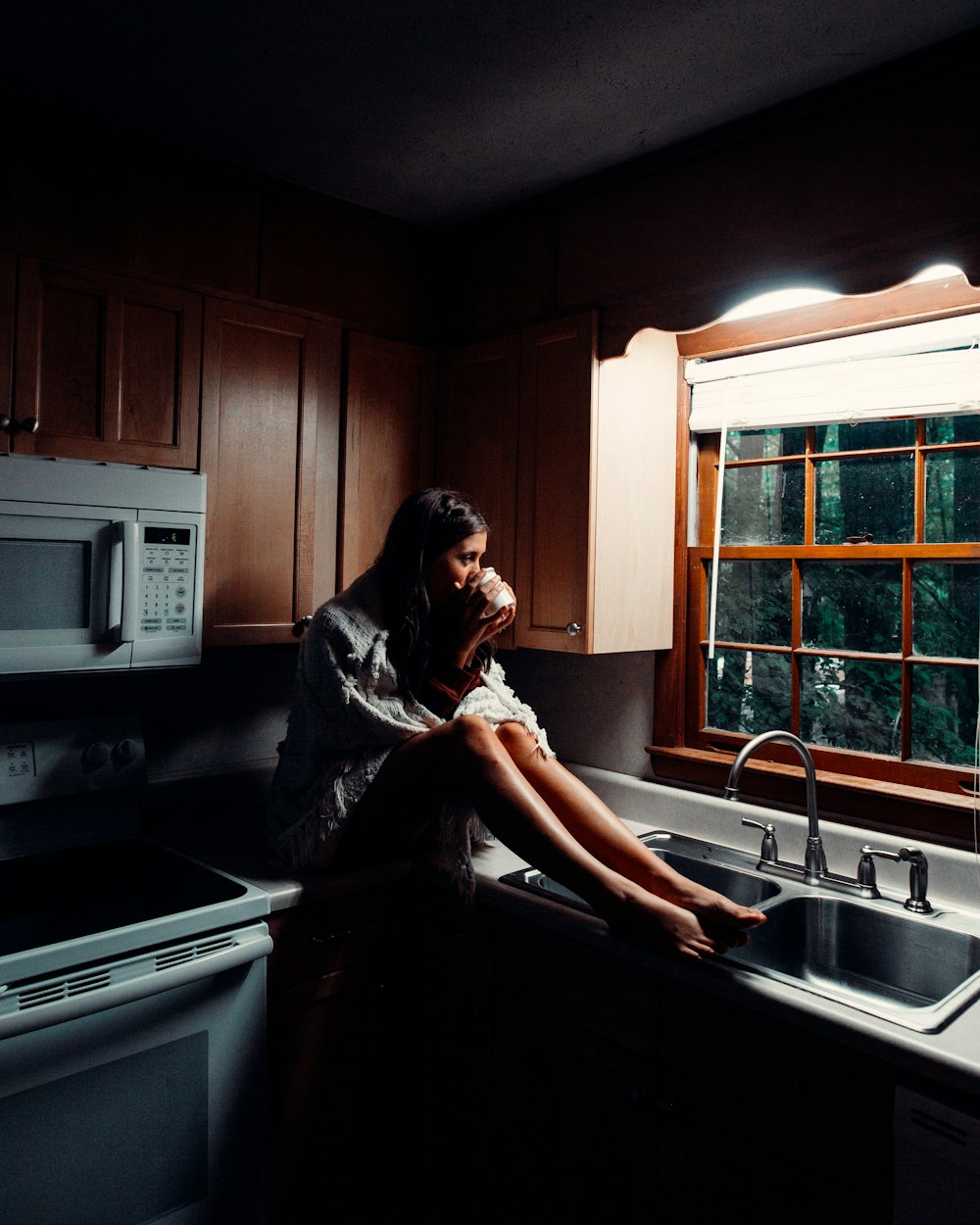 woman in black dress sitting on kitchen sink