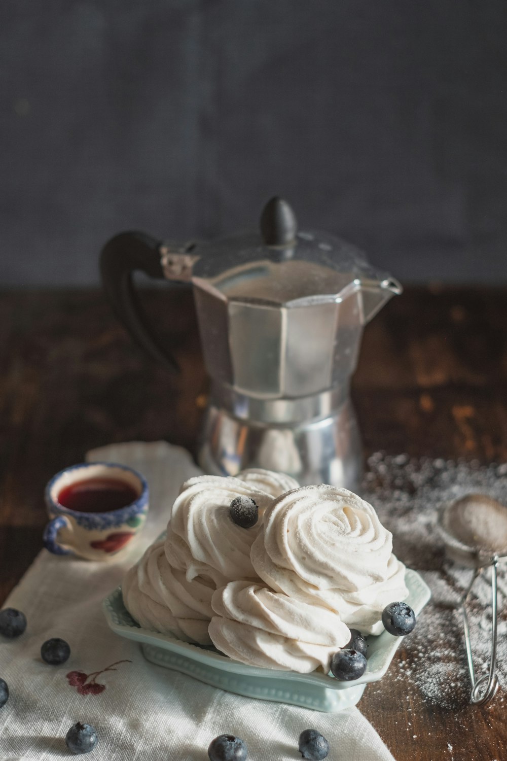 Edelstahl-Teekanne gießt weiße Creme auf weiße Keramiktasse